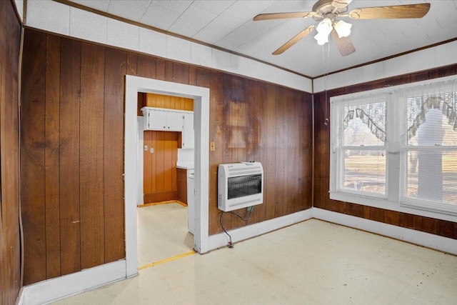 spare room featuring ceiling fan, ornamental molding, heating unit, and wood walls