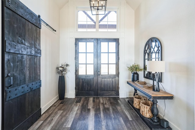 entrance foyer featuring dark wood-type flooring, a high ceiling, and a barn door