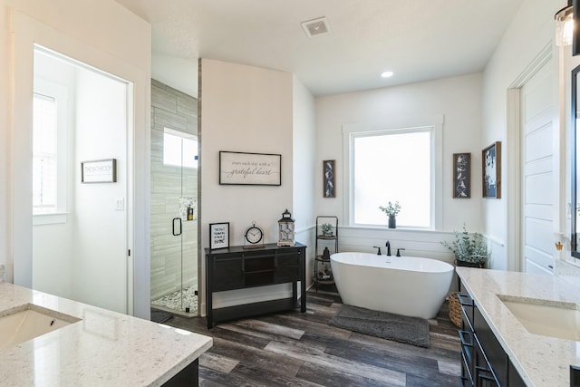 bathroom with shower with separate bathtub, a healthy amount of sunlight, hardwood / wood-style flooring, and vanity