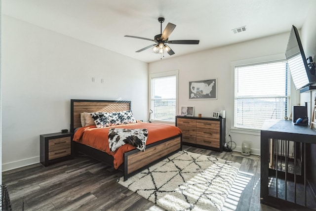 bedroom with ceiling fan, dark wood-type flooring, and multiple windows