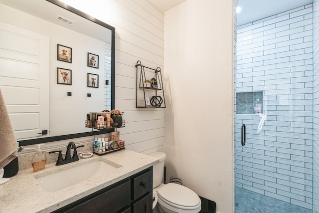 bathroom with a shower with shower door, vanity, toilet, and wood walls