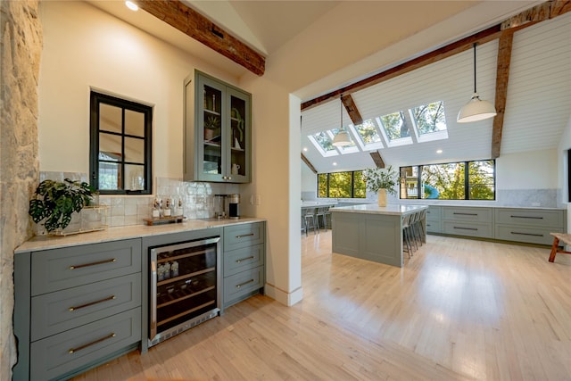 bar with decorative light fixtures, lofted ceiling with beams, beverage cooler, and gray cabinetry