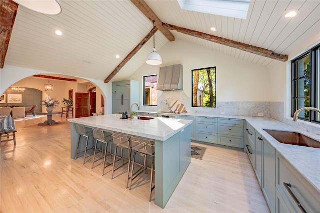 kitchen featuring sink, hanging light fixtures, a center island with sink, and a breakfast bar area