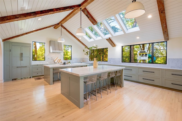 kitchen featuring a skylight, light hardwood / wood-style floors, a spacious island, decorative light fixtures, and a breakfast bar