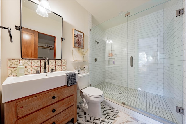 bathroom featuring toilet, vanity, tile patterned flooring, decorative backsplash, and an enclosed shower