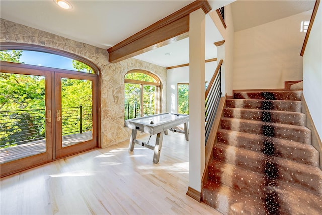 game room featuring plenty of natural light, beam ceiling, and light hardwood / wood-style flooring