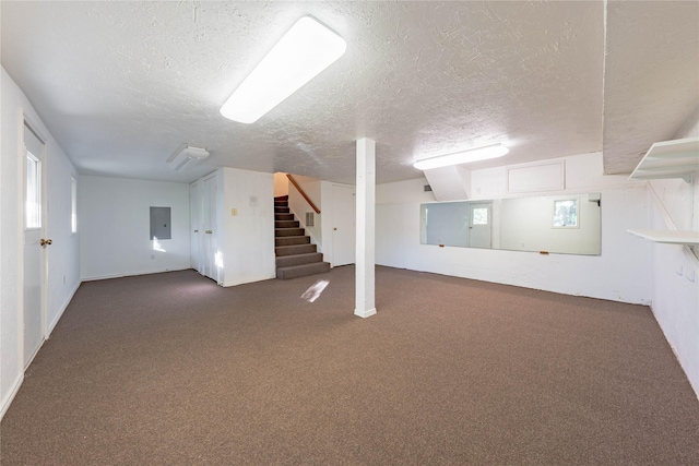 basement with plenty of natural light, a textured ceiling, electric panel, and dark carpet