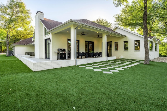 rear view of house with ceiling fan, a yard, and a patio