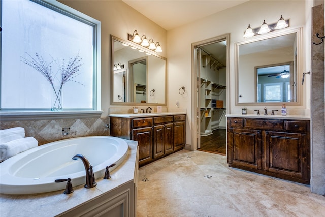 bathroom with tiled bath, vanity, and ceiling fan