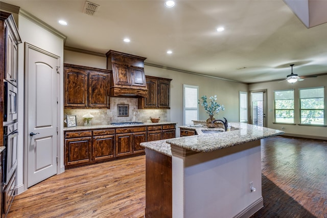 kitchen featuring light hardwood / wood-style floors, sink, an island with sink, stainless steel appliances, and dark brown cabinets