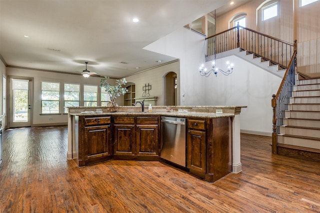 kitchen featuring dishwasher, crown molding, dark wood-type flooring, light stone counters, and ceiling fan with notable chandelier