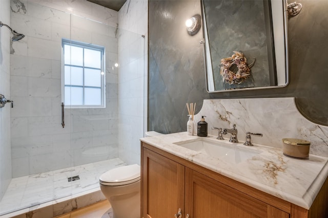 bathroom with toilet, vanity, and tiled shower