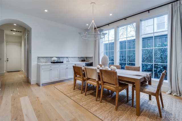 dining space with light hardwood / wood-style floors and a chandelier