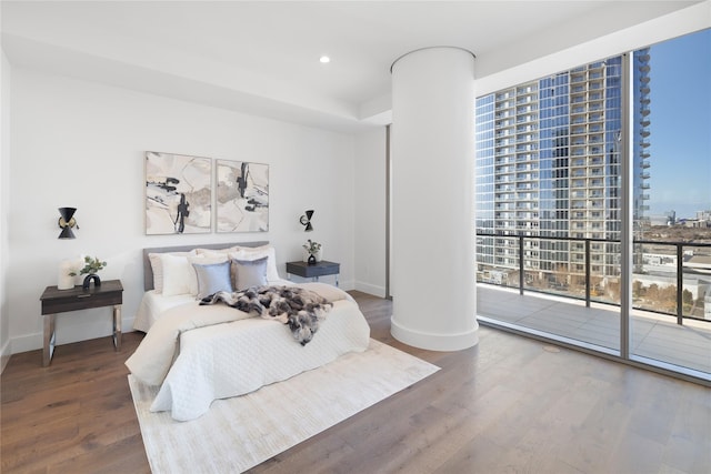 bedroom featuring access to exterior, decorative columns, floor to ceiling windows, and hardwood / wood-style flooring