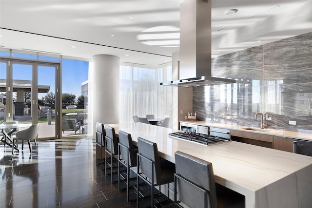 kitchen with a breakfast bar, stainless steel gas cooktop, expansive windows, and sink