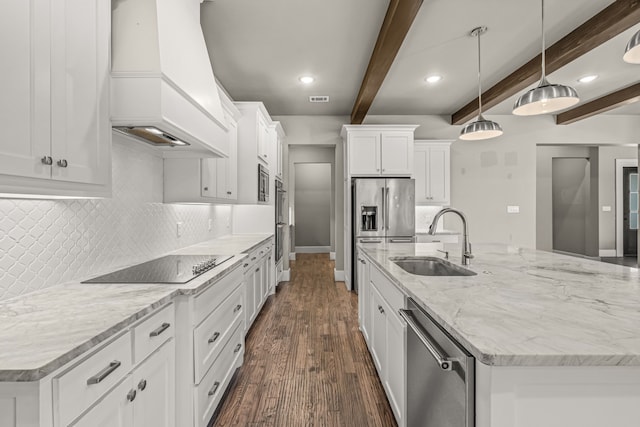 kitchen featuring custom exhaust hood, stainless steel appliances, decorative light fixtures, a kitchen island with sink, and beamed ceiling