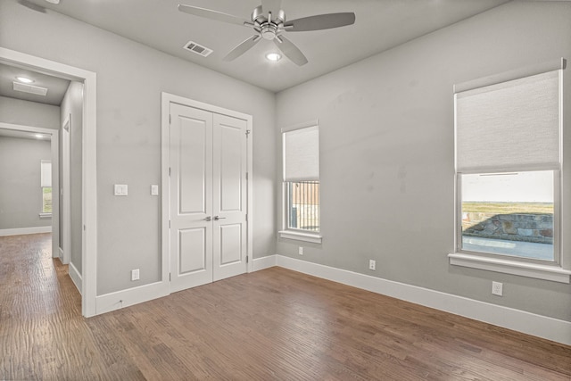 unfurnished bedroom featuring ceiling fan, a closet, and hardwood / wood-style flooring