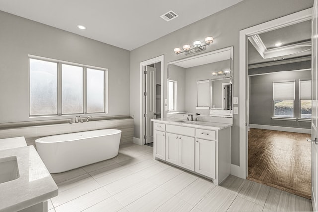 bathroom featuring tile patterned flooring, a bath, ornamental molding, and vanity