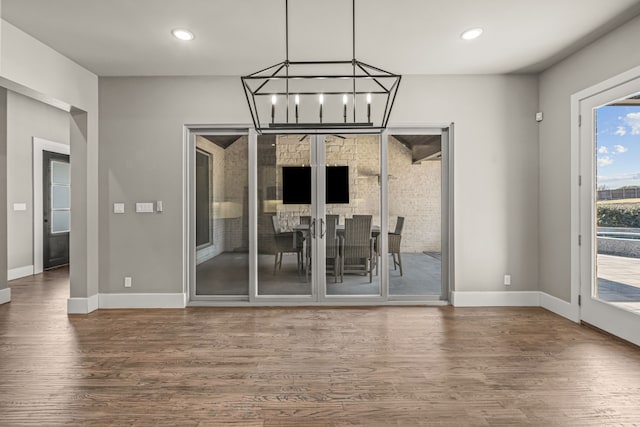 unfurnished dining area with a chandelier and hardwood / wood-style flooring