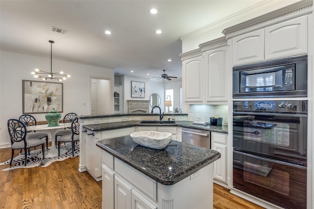 kitchen featuring kitchen peninsula, decorative light fixtures, tasteful backsplash, a center island, and black appliances