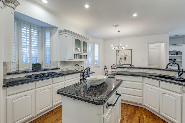 kitchen featuring white cabinetry, decorative backsplash, sink, a kitchen island, and decorative light fixtures