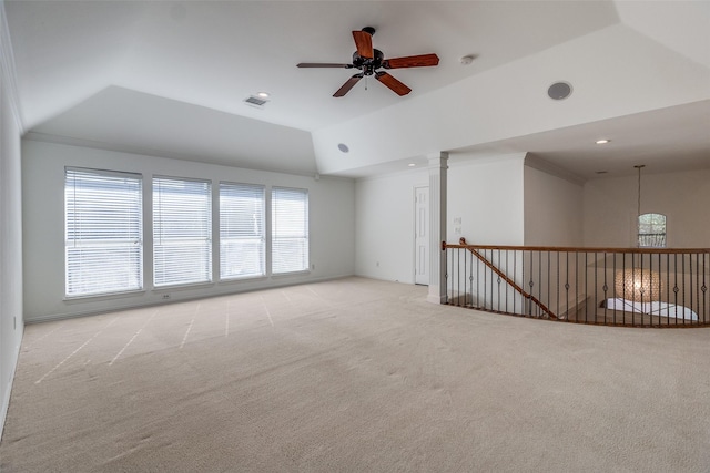 carpeted empty room with vaulted ceiling, ceiling fan, and a tray ceiling