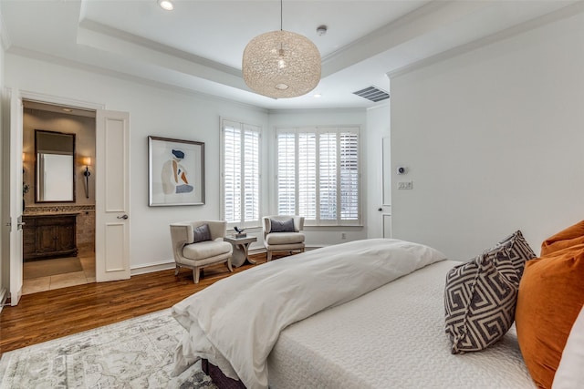 bedroom featuring ornamental molding, hardwood / wood-style flooring, connected bathroom, and a raised ceiling