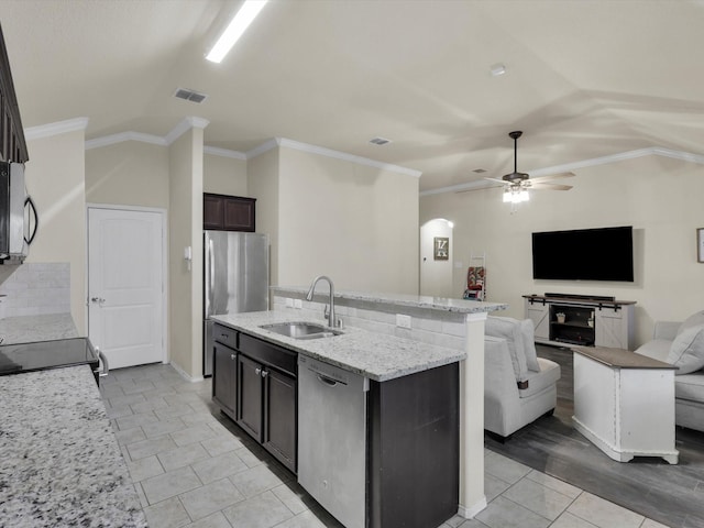 kitchen featuring stainless steel appliances, vaulted ceiling, sink, and a kitchen island with sink