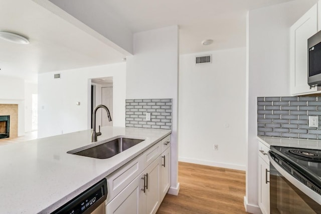 kitchen with decorative backsplash, white cabinets, light stone counters, and sink