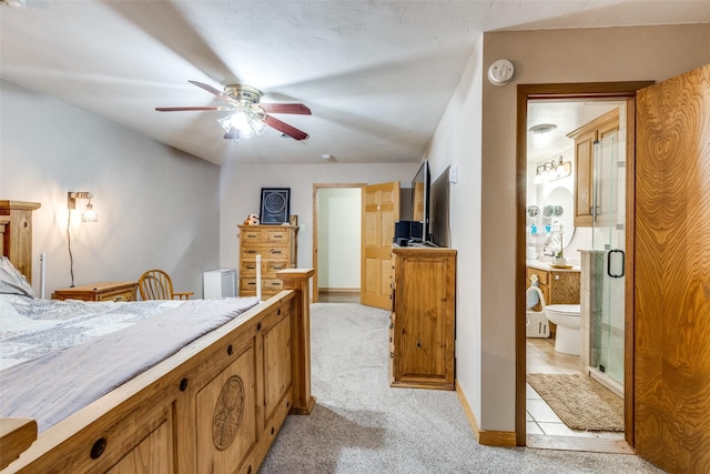 carpeted bedroom with ensuite bathroom and ceiling fan