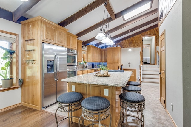 kitchen featuring stainless steel appliances, lofted ceiling with beams, pendant lighting, a breakfast bar, and a center island