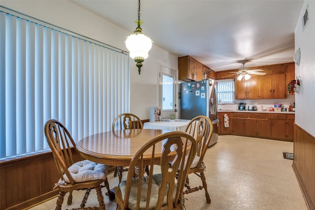 dining area featuring ceiling fan and wooden walls