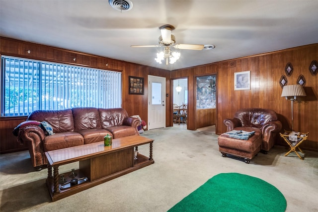 carpeted living room featuring ceiling fan and wooden walls