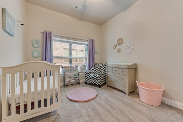 bedroom with ceiling fan, light colored carpet, and a crib