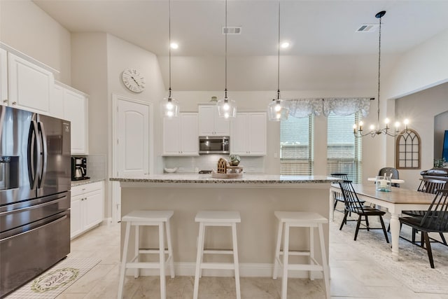 kitchen featuring white cabinets, stainless steel appliances, and a center island with sink