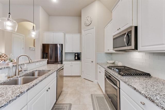 kitchen with tasteful backsplash, pendant lighting, sink, stainless steel appliances, and white cabinets