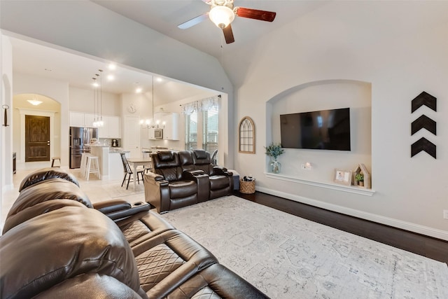 living room featuring lofted ceiling, ceiling fan with notable chandelier, and wood-type flooring