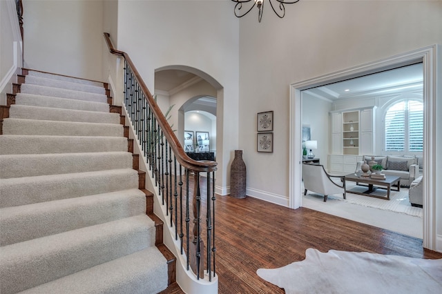 stairs featuring an inviting chandelier, ornamental molding, and hardwood / wood-style floors