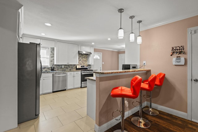 kitchen featuring white cabinets, stainless steel appliances, tasteful backsplash, kitchen peninsula, and a breakfast bar area