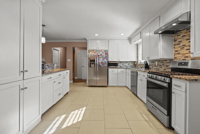 kitchen with white cabinetry, appliances with stainless steel finishes, decorative backsplash, dark stone countertops, and wall chimney exhaust hood