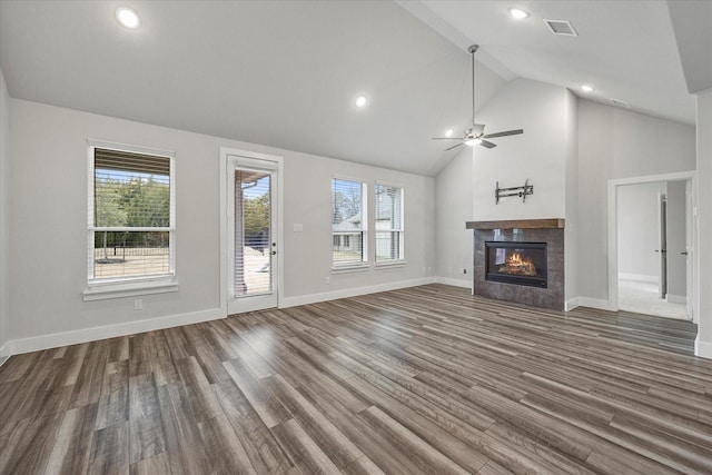 unfurnished living room featuring ceiling fan, dark hardwood / wood-style flooring, high vaulted ceiling, and a tiled fireplace