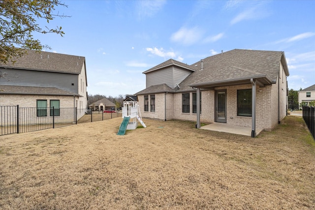 back of property featuring a playground, a lawn, and a patio