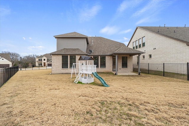 back of house featuring a playground and a lawn