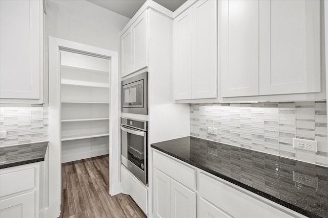 kitchen featuring appliances with stainless steel finishes, dark stone countertops, and white cabinetry