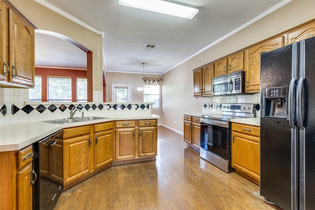 kitchen with brown cabinets, light countertops, visible vents, a sink, and black appliances