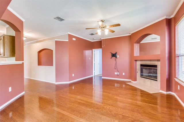 unfurnished living room with baseboards, visible vents, a ceiling fan, wood finished floors, and a fireplace