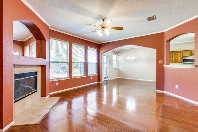 unfurnished living room featuring a textured ceiling, ceiling fan, a tile fireplace, light wood-style flooring, and visible vents