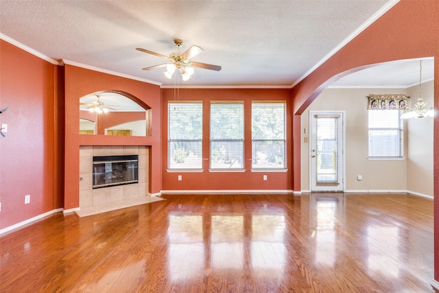 unfurnished living room featuring crown molding, a fireplace, a textured ceiling, and wood finished floors