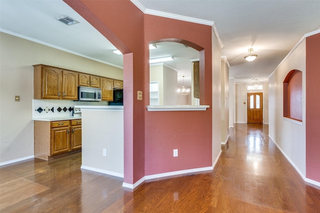 kitchen featuring brown cabinetry, light countertops, stainless steel microwave, and wood finished floors