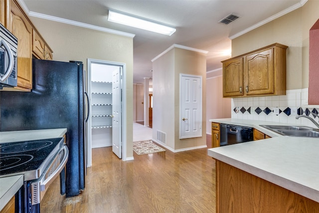 kitchen with brown cabinets, light countertops, visible vents, and a sink